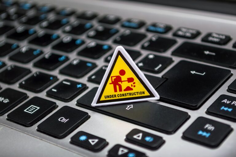 closeup of laptop keyboard with a superimposed yellow and red 'under construction' sign
