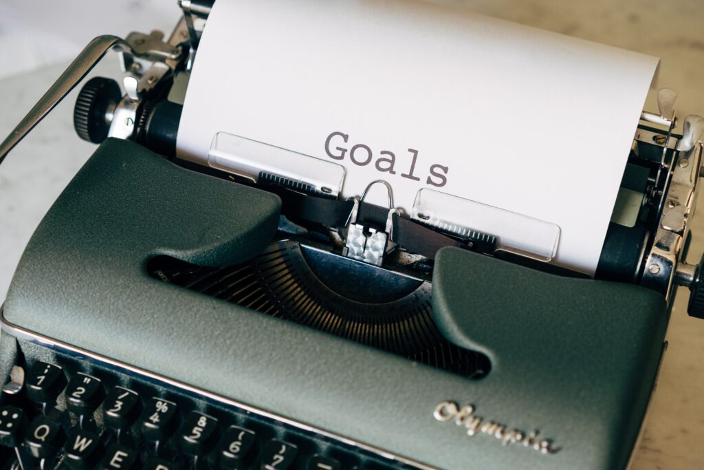 a typewriter zoomed in on the paper coming out of it, on which the word 'goals' has been typed
