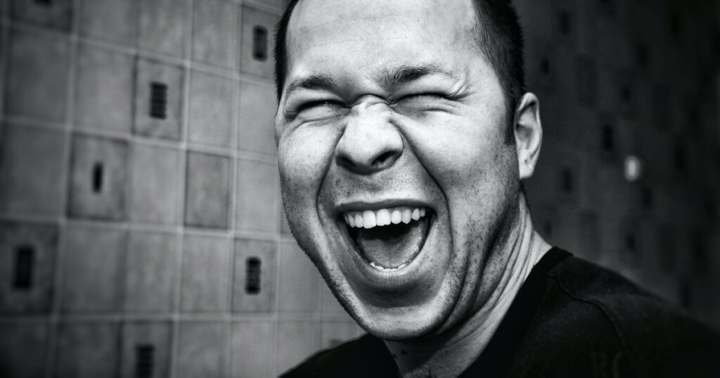 Black and white portrait of a man laughing with what seems to be genuine mirth